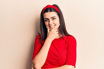 Young beautiful girl wearing casual t shirt and diadem looking confident at the camera smiling with crossed arms and hand raised on chin. thinking positive.