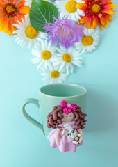 The original mug with decorative figurines made with their own hands. A lovely birthday present. Figures on the cup are fashioned hand made from colored clay. Fresh flowers background.