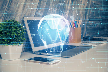 Computer on desktop in office with bulb icon hologram. Multi exposure. Concept of idea.