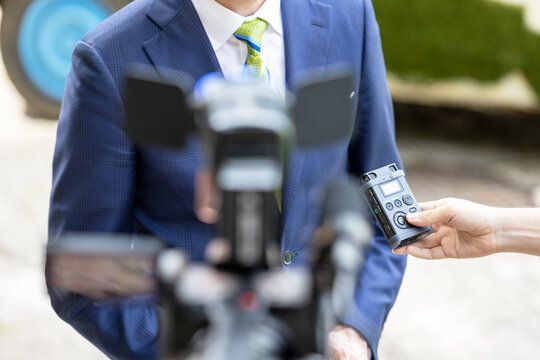 Journalist holding voice recorder making media interview with politician or business person