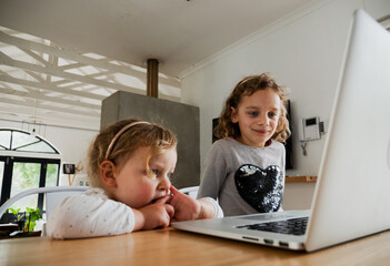 Young caucasian sisters watching and learning on the laptop together