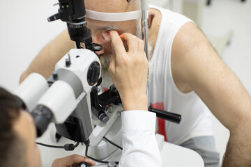 Senior patient checking vision with special eye equipment