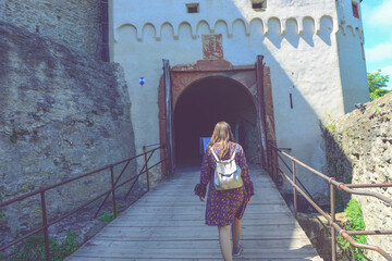 Woman walking on a bridge to an old fortress entrance, gate
