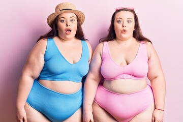 Young plus size twins wearing bikini scared and amazed with open mouth for surprise, disbelief face