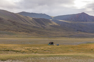 Tourists camping in Mongolian hills. Three tents under the open cloudy sky.