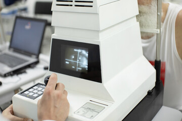 Doctor Optometrist examining bearded senior man eyes with special eye equipment.