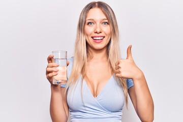 Young beautiful blonde girl drinking glass of water smiling happy and positive, thumb up doing excellent and approval sign
