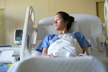 Asian chinese woman patient lying in hospital ward and looking out of the window