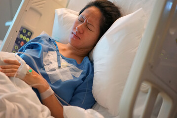 Asian Chinese Woman patient lying in the hospital bed in pain