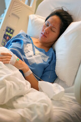 Asian Chinese Woman patient lying in the hospital bed in pain