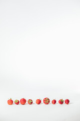 strawberries arranged in a straight line on a white background and with a lot of free space