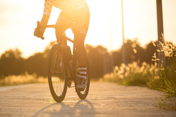 Woman cyclist legs riding Mountain Bike on highway sun set , hi key