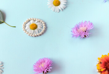 live flowers, jewelry and green leaves of trees on a blue background. A beautiful postcard for a loved one. Flat lay. High quality photo