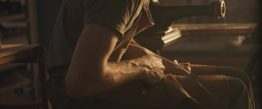 Shoemaker cut leather insole on a wooden shoe last with knife in small business reopened workshop with magic light make traditional bespoke shoes