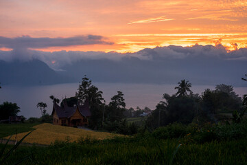 The traditional Minangkabau house is located in the middle of rice fields and behind it is a lake