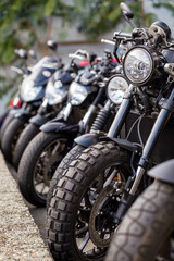 Vertical close-up detail of brand-new motorcycles parked in a row, in a motorbike dealership. Several bikes for sale