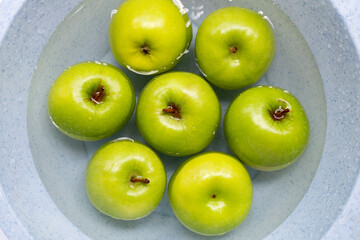 Soak green apples in water. Washing fruit concept