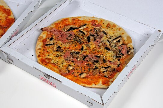 Ham and mushroom pizza in a cardboard take-away box.