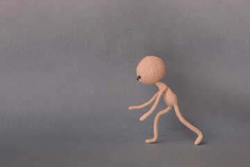 A toy man on a gray background with copy space. Cute amigurumi. Presentation PowerPoint or Keynote. Motivational phrase. Man rolls the object on the floor