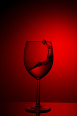 Fototapeta na wymiar A splash of red wine in a glass on a red background