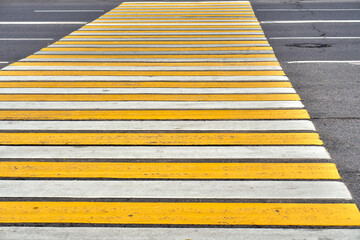 Crosswalk. Road markings. Road zebra. Yellow and white stripes.