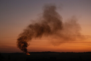 Smoke rises from burning sugarcane at dusk in Hillcrest, South Africa, 1 June 2020. The sugarcane is burnt to ease the harvesting process.