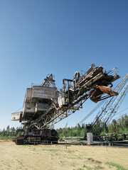 Fototapeta na wymiar Giant old absetzer rusts in a sand quarry. Huge mining excavator.