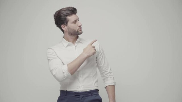 Young handsome businessman indicates something with his hands. Isolated on gray background