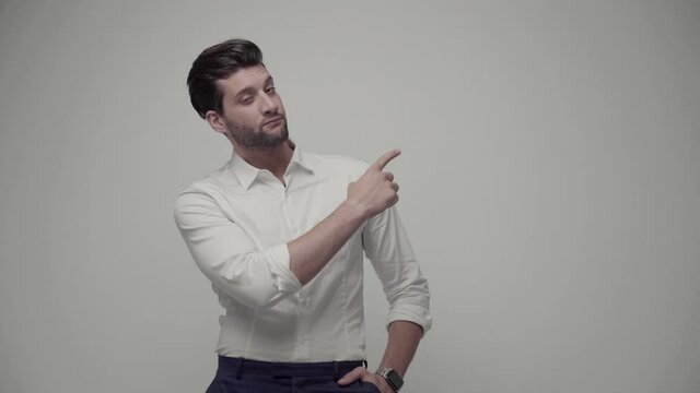 Young handsome businessman indicates something with his hands. Isolated on gray background
