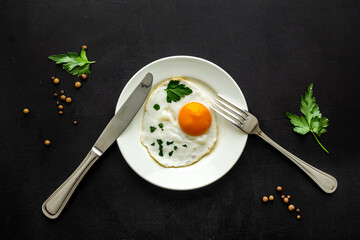 Fried eggs on plate - black table top view