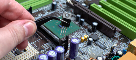 A human hand holds a chip on a white background with tweezers. Electronics repair shops. Disassembled lcd TV. Radio-electronic components. LCD TV circuit Board. Master electronic engineer.