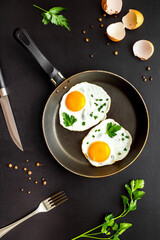 Fried eggs on frying pan on black desk top-down