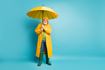 Full length body size view of his he dissatisfied mad irritated grey-haired man fisherman wearing yellow topcoat bad weather day isolated over bright vivid shine vibrant blue color background
