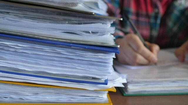 defocused accountant working in office with documents, binders full of documents