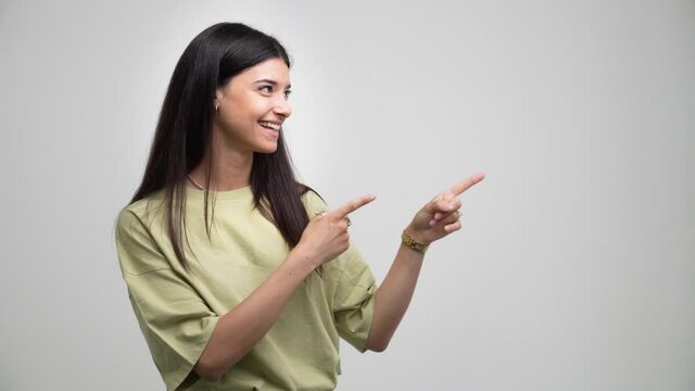 Young handsome caucasian girl indicates something with his hands. Isolated on grey background
