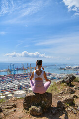 Seated woman practicing meditation outdoors away from the city and looking out to sea