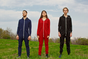 Two guys and a girl have a rest in the park on the nature. Dressed in tracksuits. Healthy lifestyle. Emotions, joy, fun, happiness, friendship.