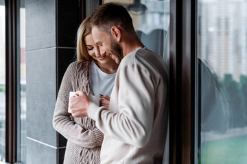 cheerful couple holding cups of coffee outside