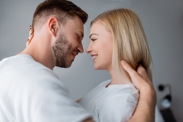 side view of cheerful couple smiling while looking at each other