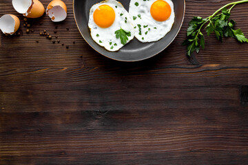 Fried eggs on frying pan - breakfast - on wooden table from above space for text