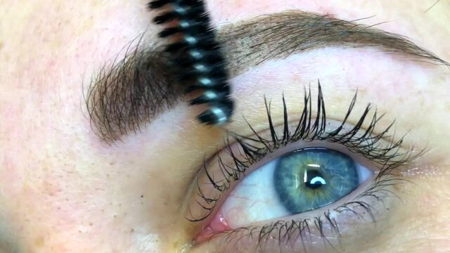 Beautician female applies permanent makeup on eyebrows. High quality 4k footage.