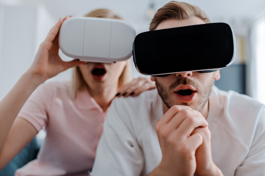 selective focus of surprised couple in virtual reality headsets gaming at home