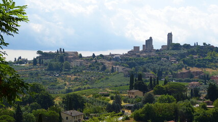 Fototapeta na wymiar Blick auf San Gimignano in der Toskana im Sommer mit Hügellandschaft, Landgut, Olivenhainen und Zypressen