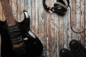 Naklejka premium guitar on a wooden background with headphones