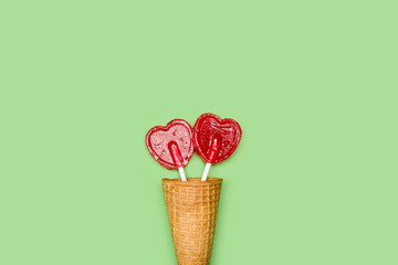 Piruletas rojas dulce y sabrosa en forma de corazón dentro de un cono de oblea de helado sobre un...