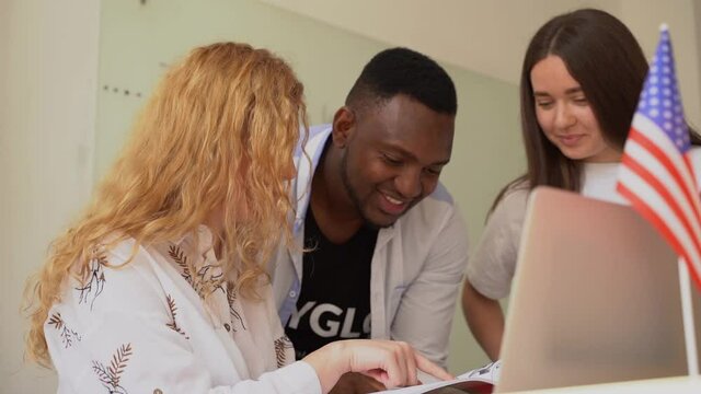 Multiethnic happy students and black teacher study foreign languages and smile and laught together in class. Studing with laptop. Black handsome student study with white people together.