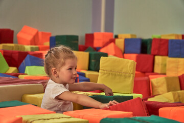 A girl gymnast plays in a multi-colored gymnastic sponge cube. Colorful baby cubes. Soft for...