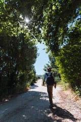 Young man with backpack and hat walking on a path in the forest. Selective focus.