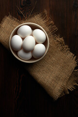 white eggs in bowl on burlap napkin on wooden rustic background.