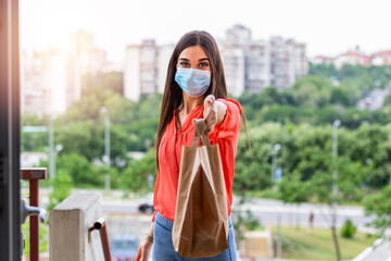 Woman delivering food in paper bag during Covid 19 Coronavirus outbreak.Feme volunteer holding...